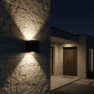 A sleek black, cubic outdoor wall light casts two cones of warm, inviting light—one upward and one downward—on a textured stone wall at night. In the background, a modern house with a dark wooden door and large windows is dimly lit under a starry sky.