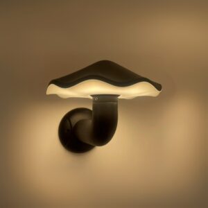 Modern black mushroom-shaped outdoor wall light or sconce mounted on a white exterior wall providing warm LED illumination for a porch or patio