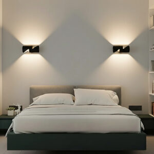 A modern black up-down wall light mounted on a gray wall, casting warm white light both upwards and downwards. The light is suitable for both indoor and outdoor use.