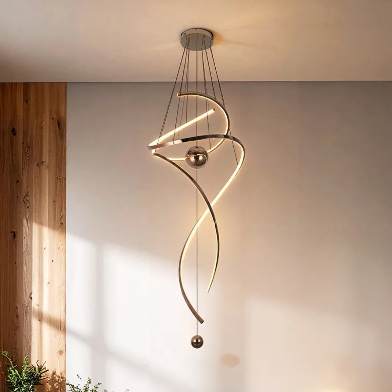 Modern spiral LED pendant light for high ceilings with metallic finish and spherical accents in a contemporary home foyer