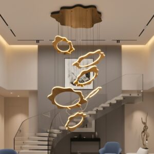 Modern gold LED chandelier in a high-ceiling luxury living room, illuminating a staircase and sofa with a warm glow.